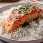 Healthy portion of roasted salmon and seasoned rice on a dish.