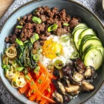 Close-up of a Korean bibimbap bowl featuring marinated beef and a fried egg