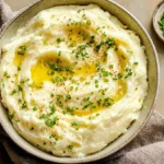 Close-up of rich, fluffy creamy mashed potatoes in a white serving dish