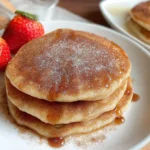 Golden-brown churro pancakes topped with cinnamon sugar and whipped cream